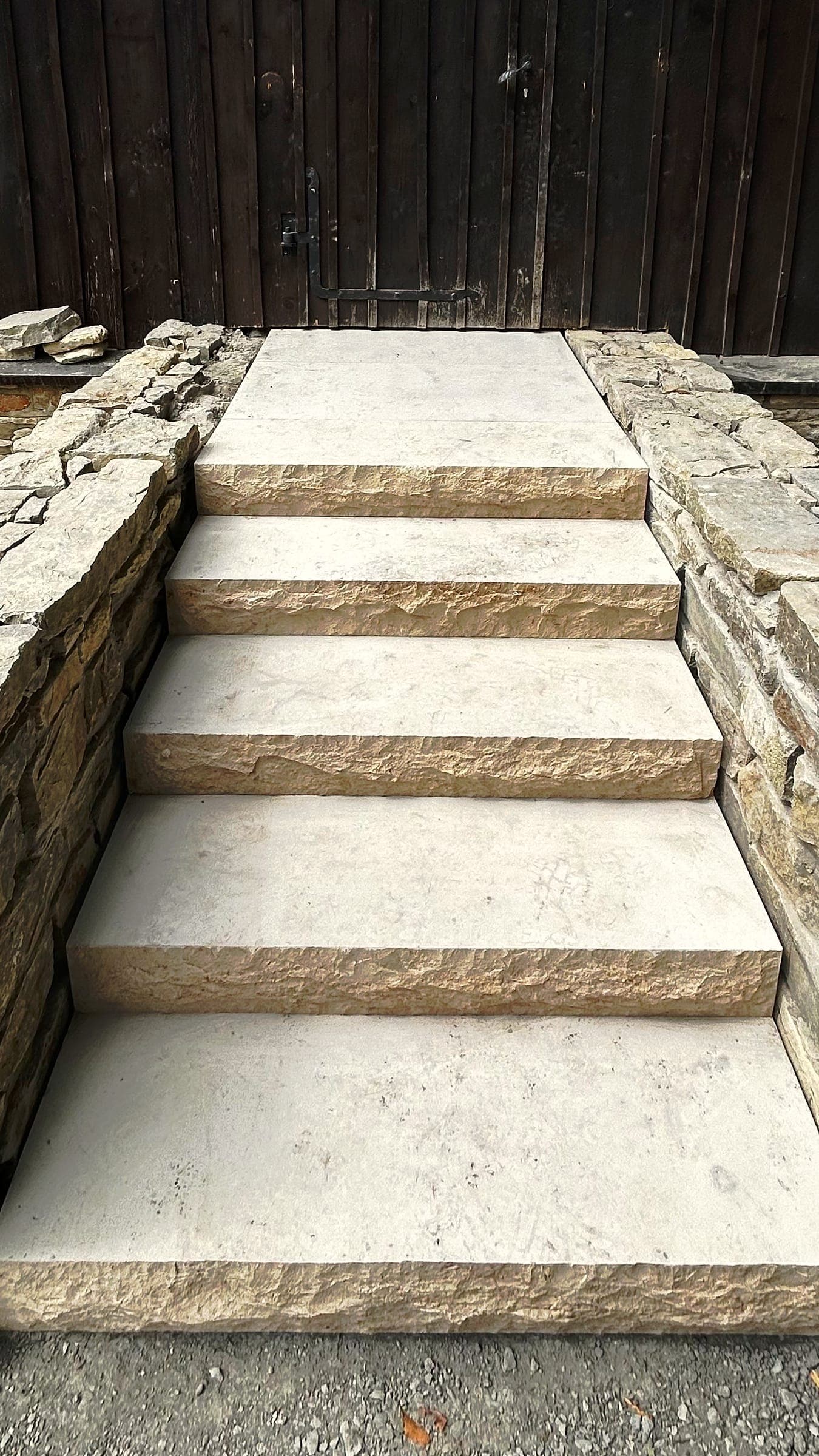Fertige Treppe aus Sandsteinstufen zwischen Trockenmauern vor einer Holztür